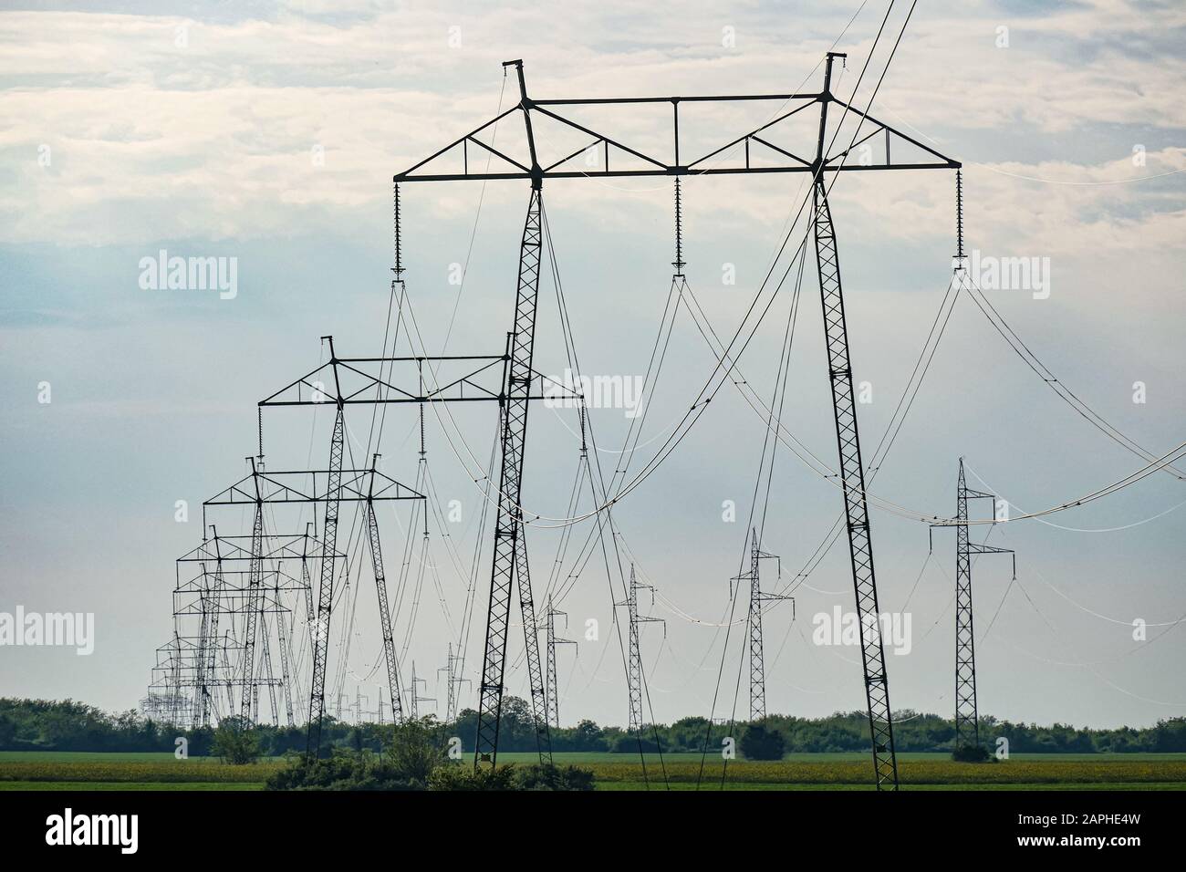 A number of high voltage electricity poles in the field. Shot below. Sky background graphic. Stock Photo