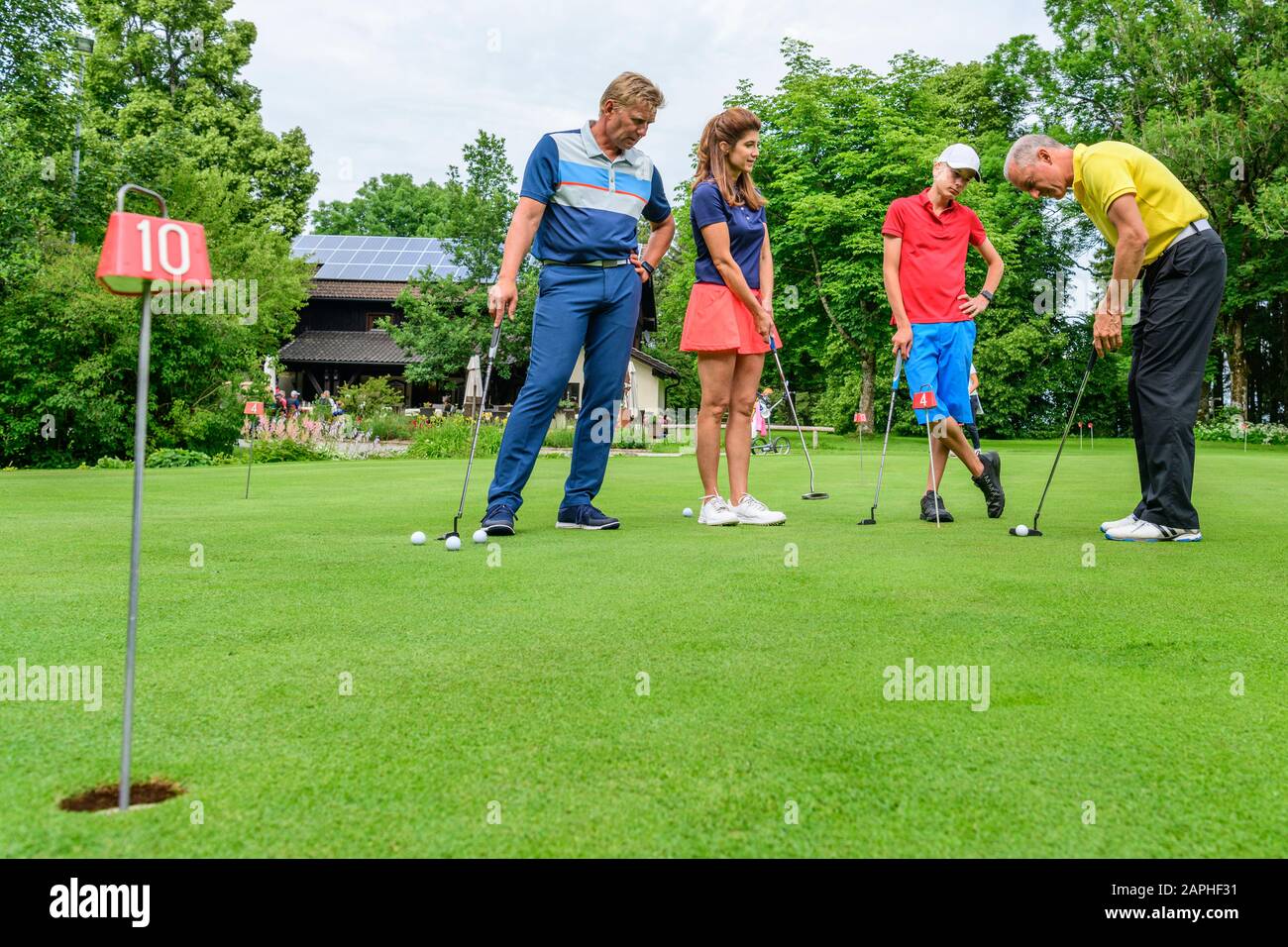 Golf players practising with golf pro on putting green Stock Photo Alamy