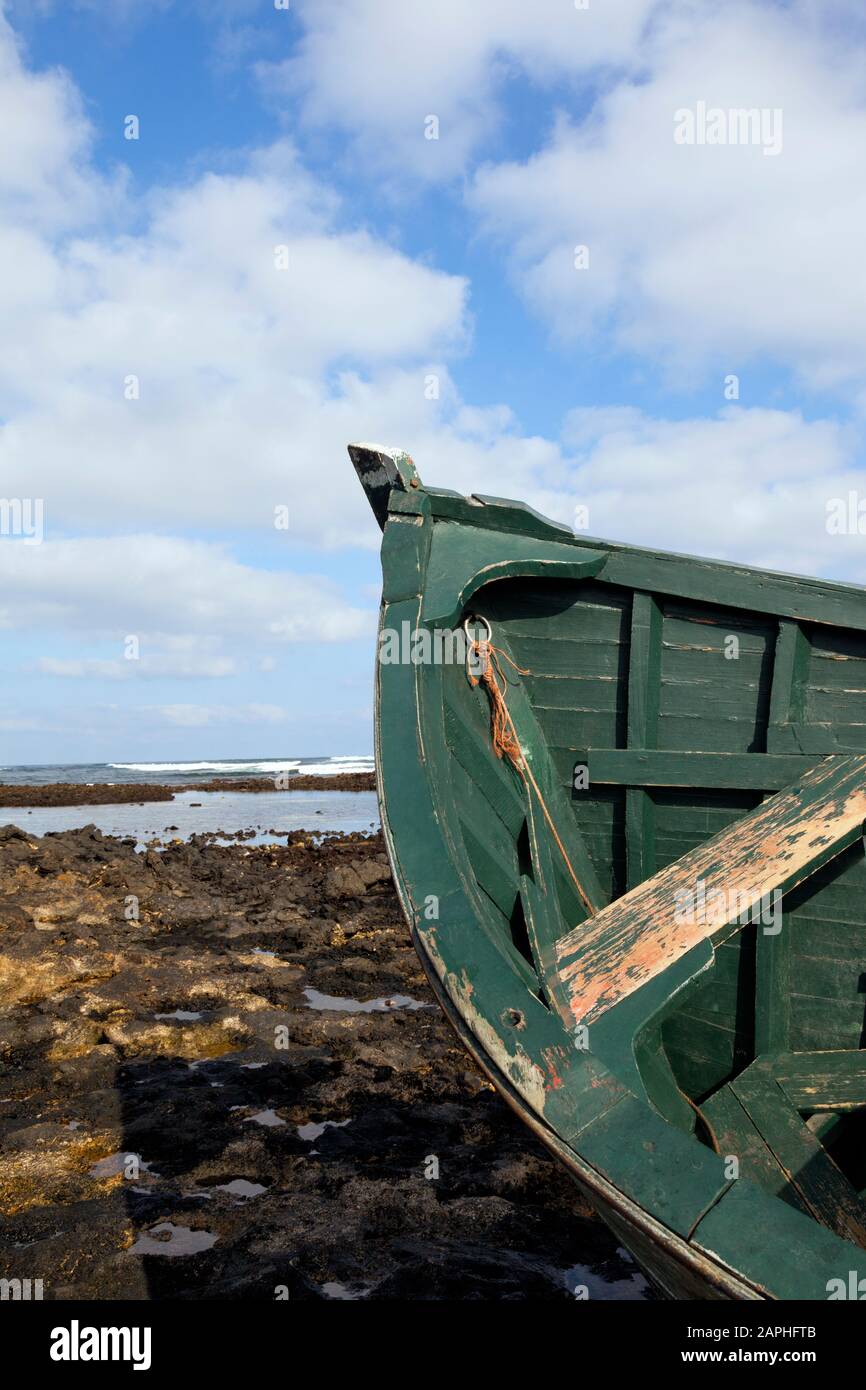 Top of green wooden fishing boat wreck stranded on beach with reef rocks, tide out . Stock Photo