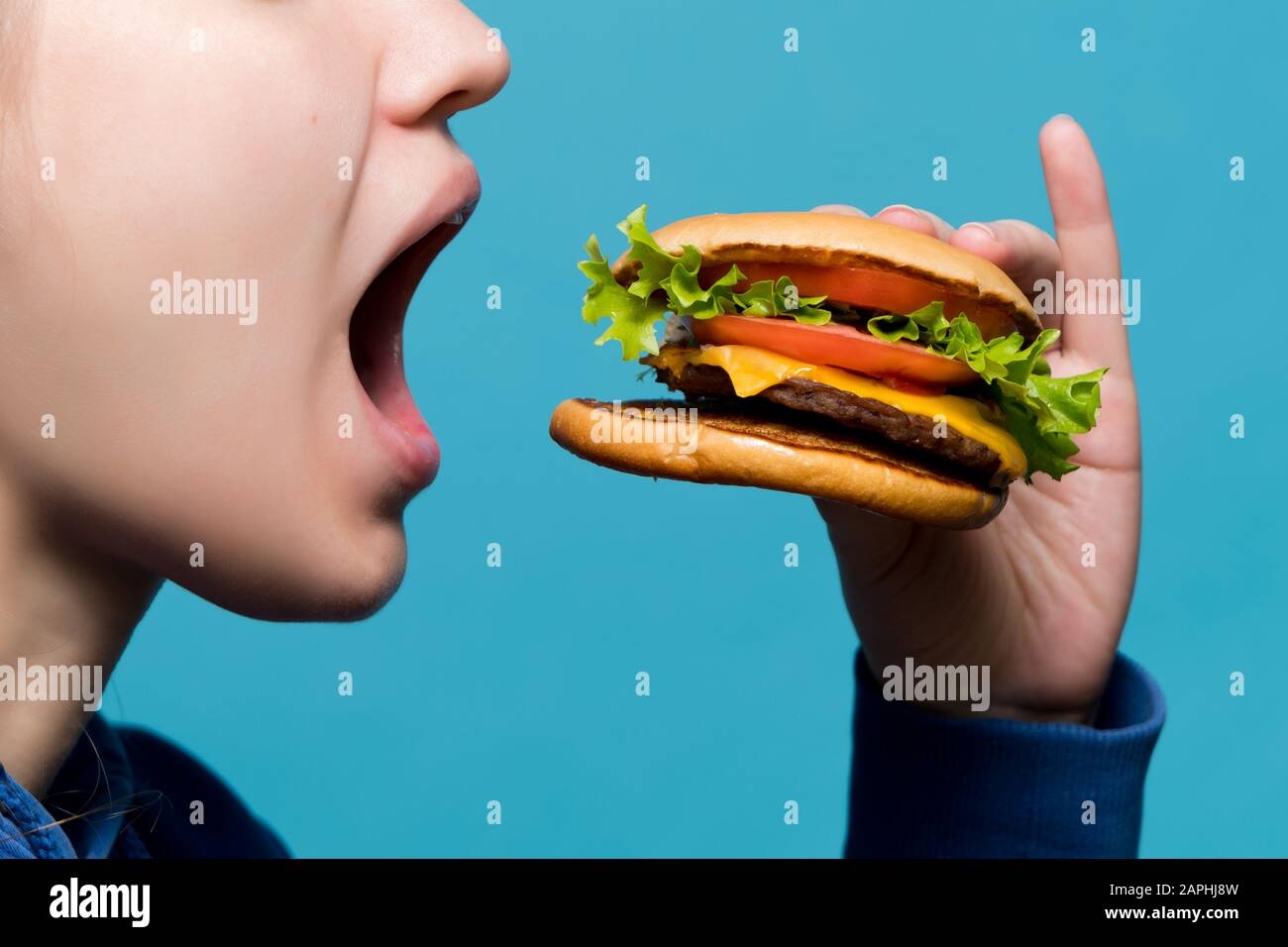 close-up of how a burger goes into a girl's mouth, side view Stock Photo