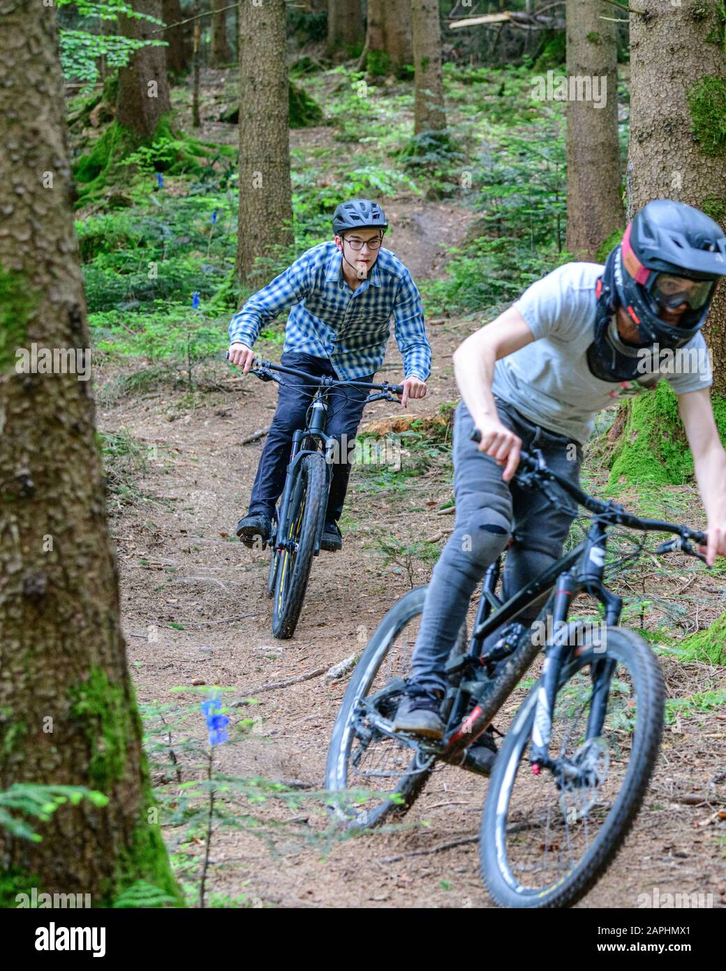 Mountainbike riders doing a courageous downhill on forest trails Stock
