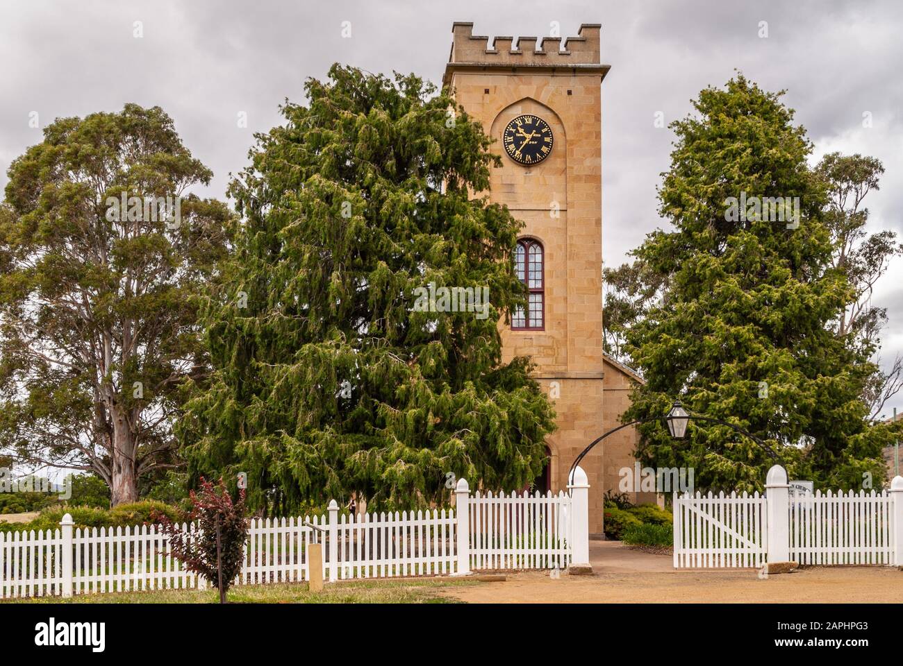 Richmond, Tasmania, Australia - December 13, 2009: Saint Luke Church. Beige stone tower with entrance and dominant clock, set trees with Stock Photo -
