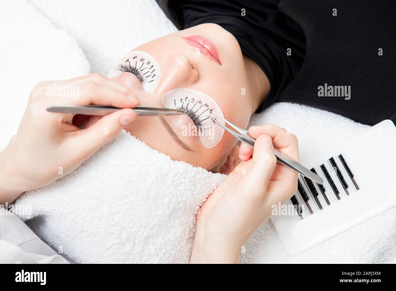 Eyelash extension procedure. Master tweezers fake long lashes beautiful