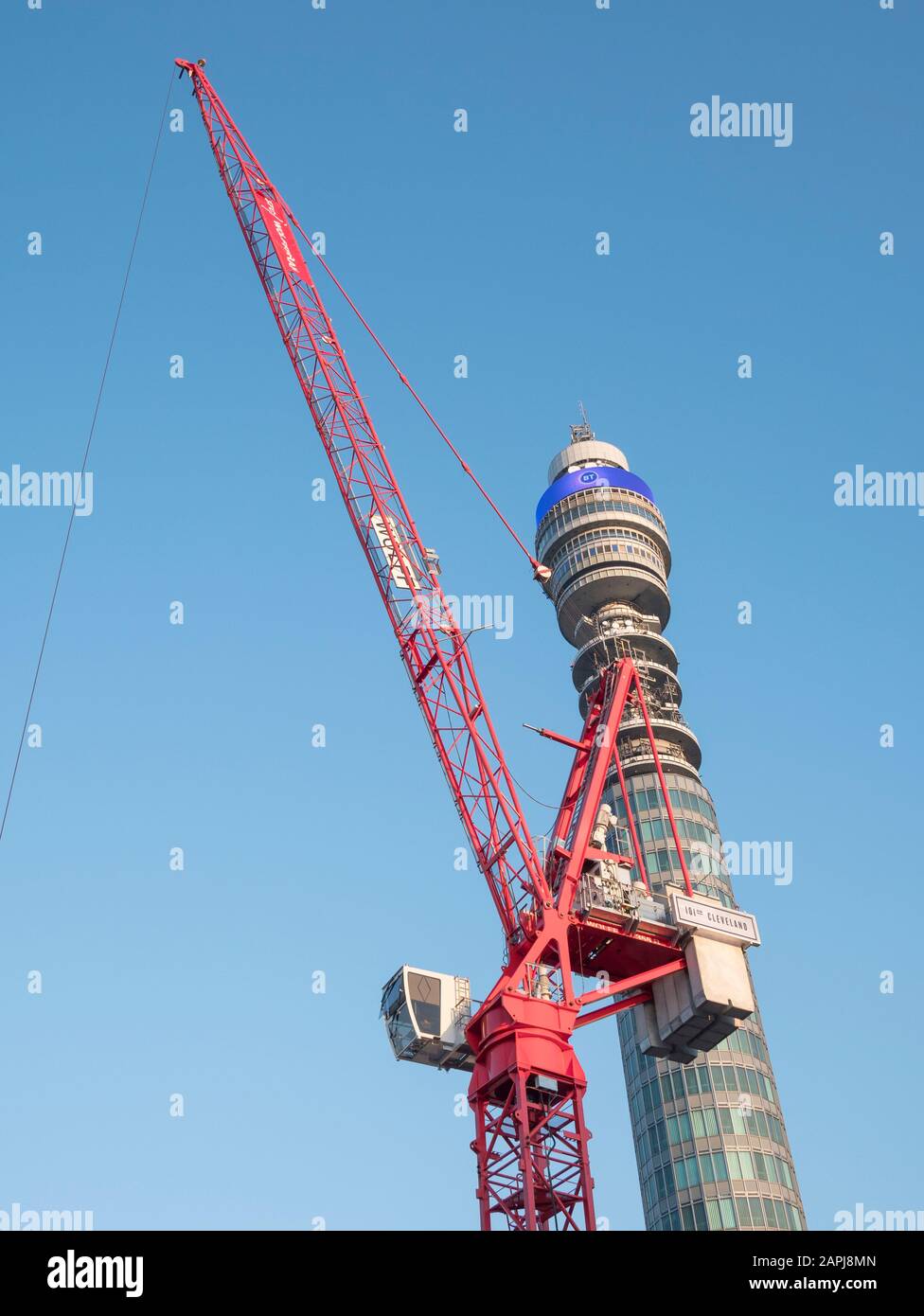 Red tower crane and Post Office Tower set against blue sky in Spring sunshine. Metaphor London construction activity, new builds, London sightseeing. Stock Photo