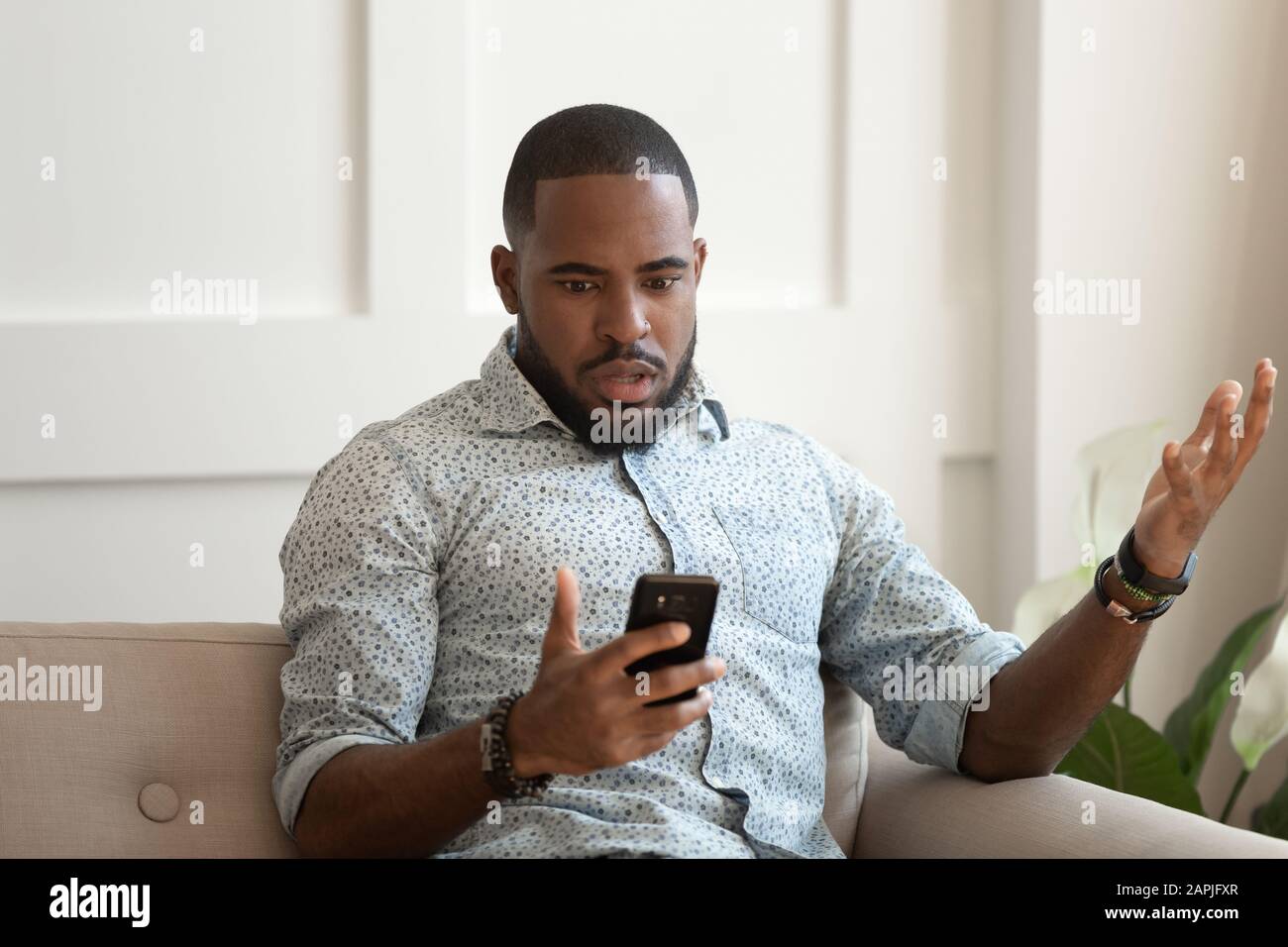 African man holds cellphone read sms feels shocked Stock Photo
