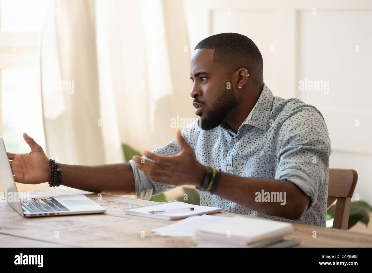 African guy looks at pc screen talking feels outraged Stock Photo