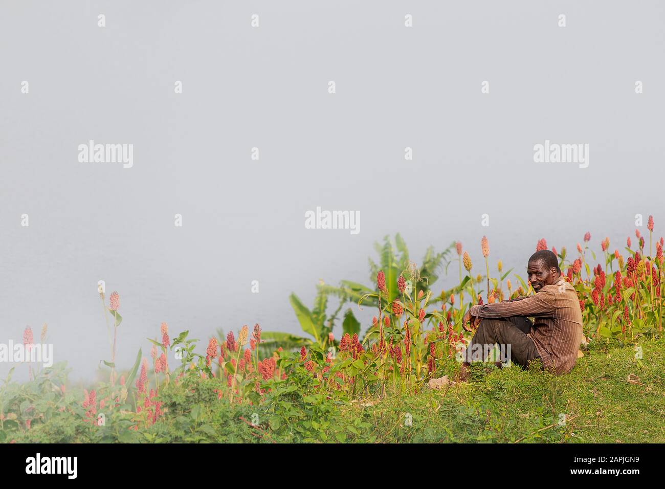 Man from Batwa tribe known also as Pygmies, sitting all by himself in the nature, at the Lake Bunyonyi, Uganda Stock Photo