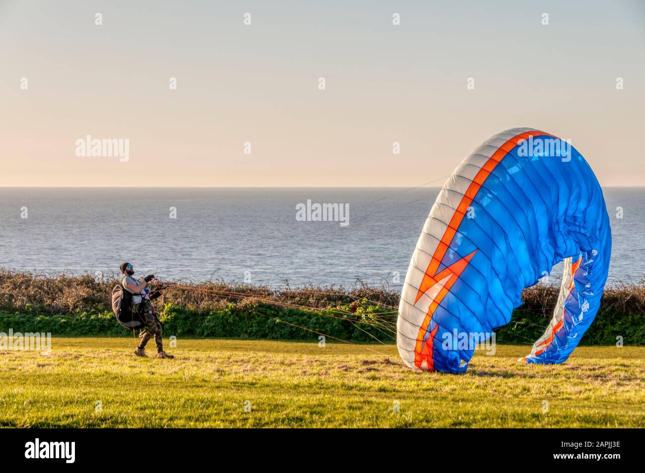 A man trying to get a colourful parasail airborne on top of Hunstanton cliffs. Stock Photo