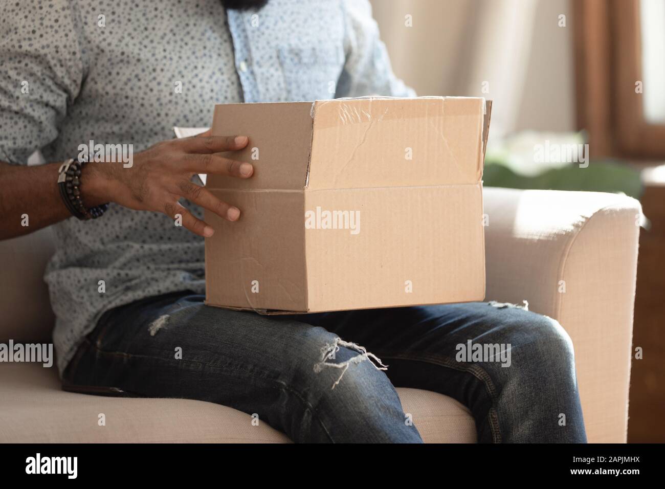 Close up view carton box on african guy lap indoors Stock Photo
