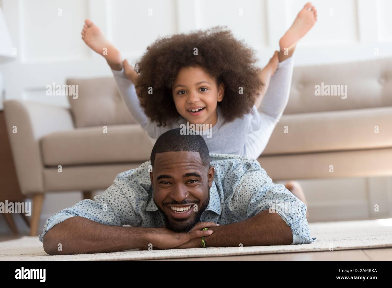 African daughter performs yoga boat pose on father back Stock Photo