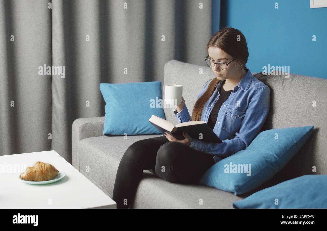 Girl reading resting on sofa Stock Photo Alamy