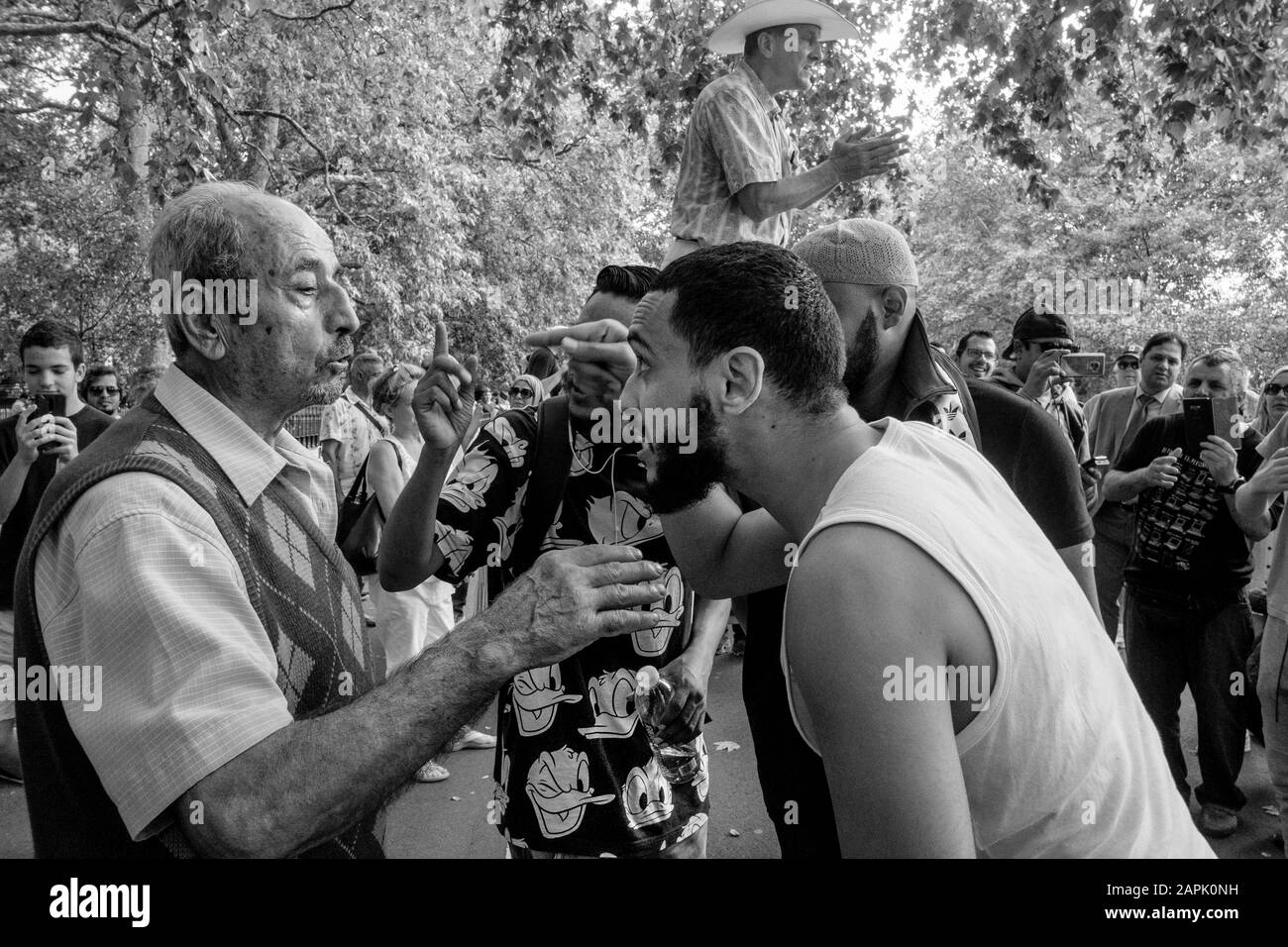London black and white street photography: Three youths and an elderly man engage in heated debate, Speakers' Corner, Hyde Park, London, UK Stock Photo