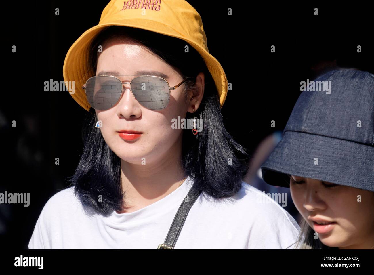 London street:  female, 20s, ethnic Chinese, sunglasses, hat. Stock Photo