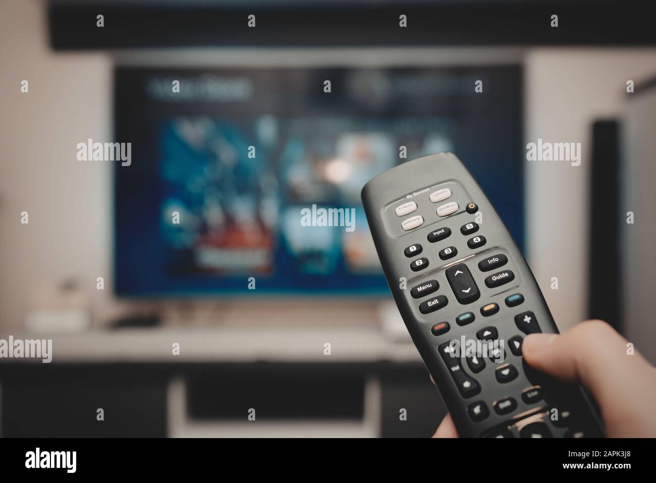 VOD service on television. Man watching TV, streaming service, video on demand, remote control in hand. Stock Photo