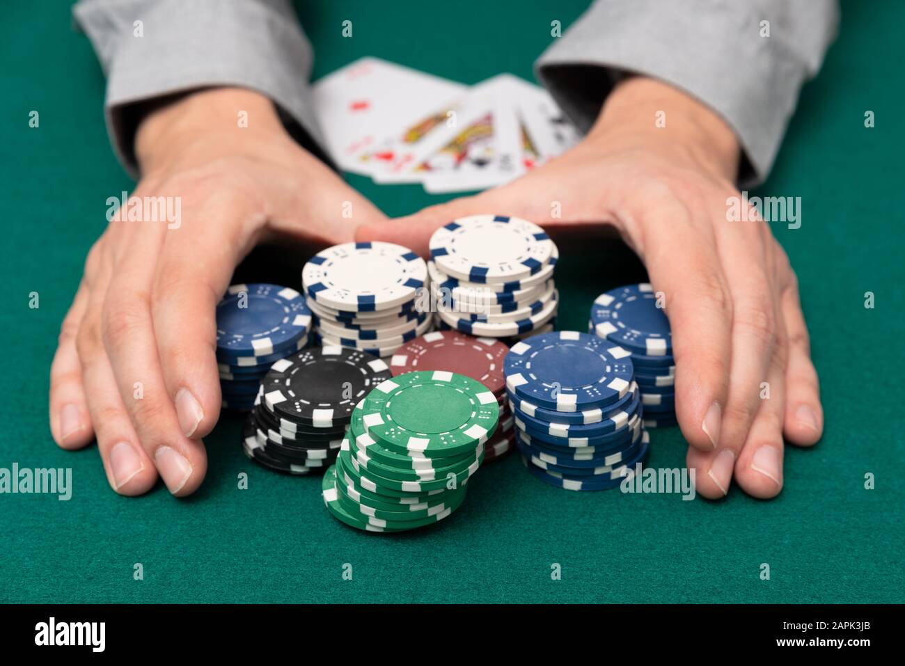 Man plays poker in the casino. Man collecting stack of poker chips, gambling concept. Stock Photo