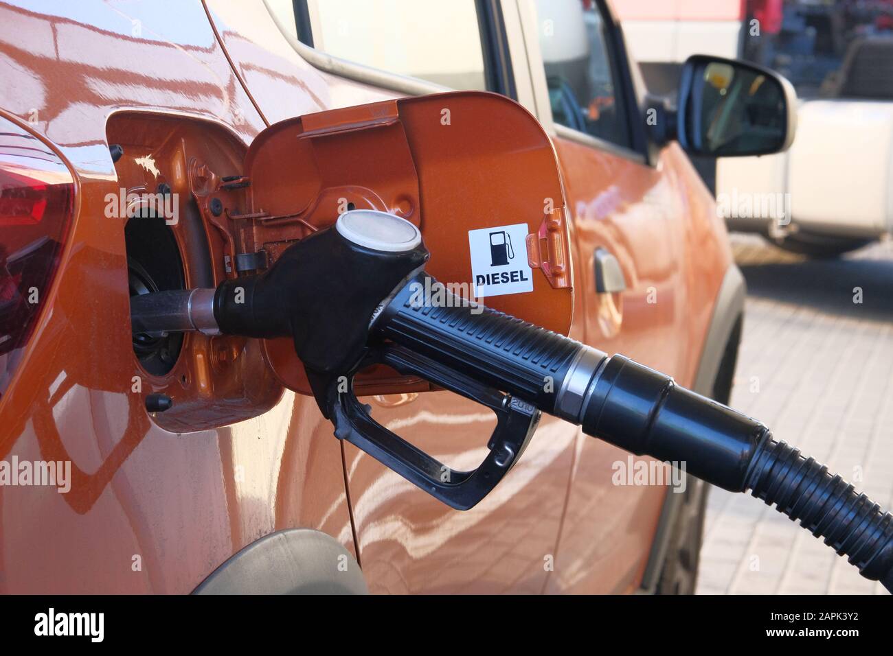 Car fill with diesel at gas station. Pumping diesel fuel in orange car at gas station close up. Stock Photo