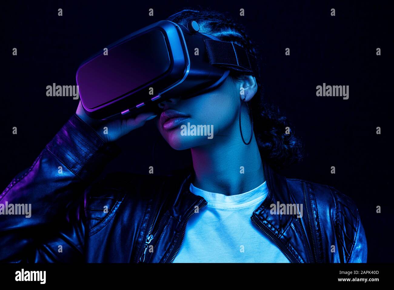 African-American young woman in vr glasses watching 360 degree video with a virtual  reality headset isolated on a black background in neon light Stock Photo -  Alamy