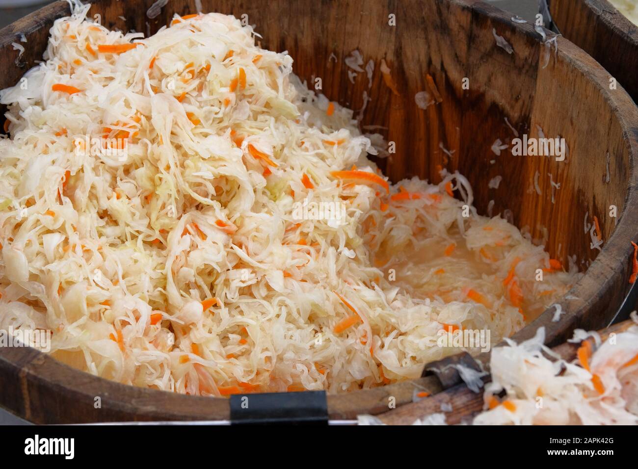 Fermented preserved vegetarian healthy food concept. Sauerkraut with orange carrots in wooden container is sold by weight in local market. Stock Photo