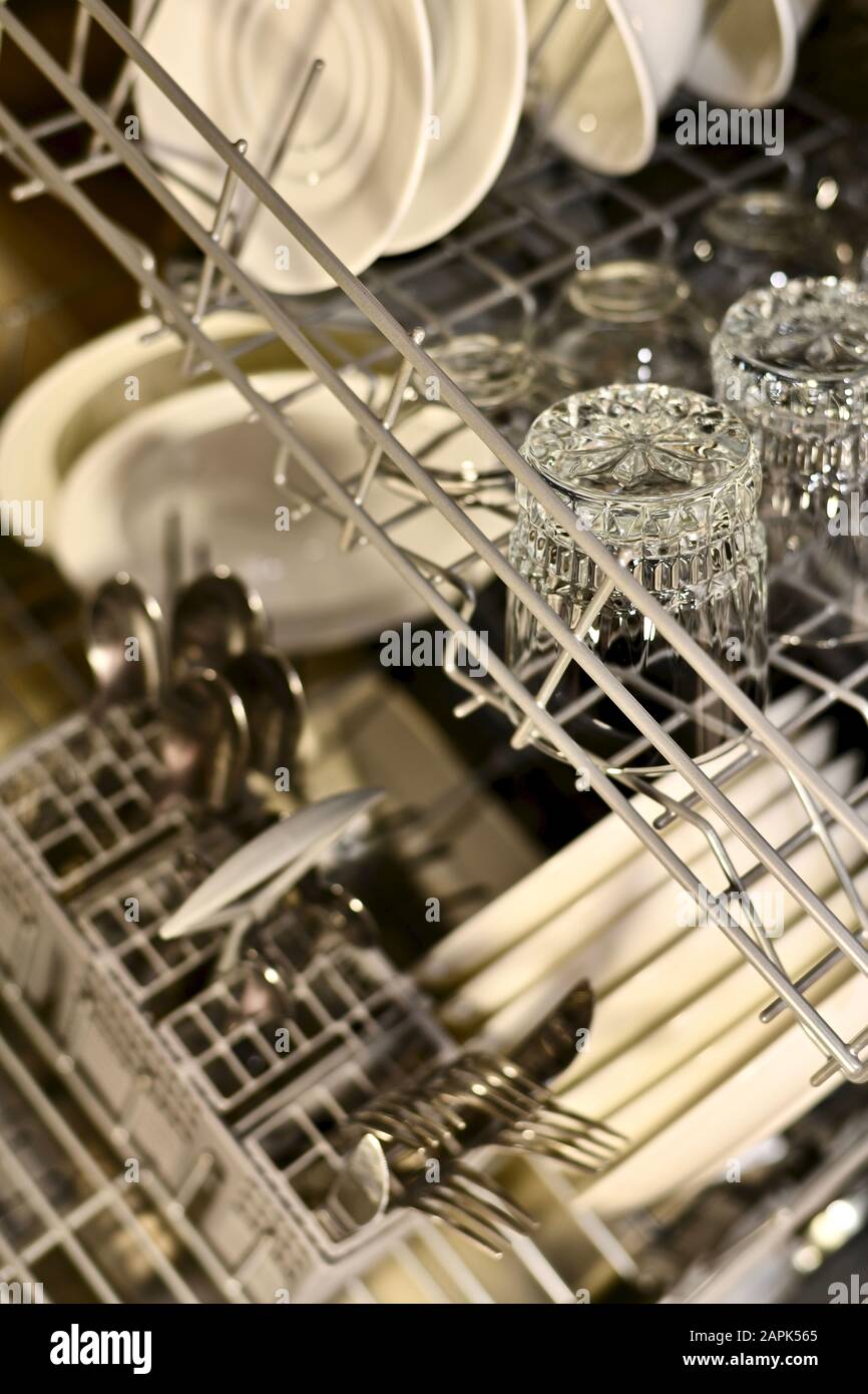 Washed dishes in a dishwasher on two shelves of a basket with an