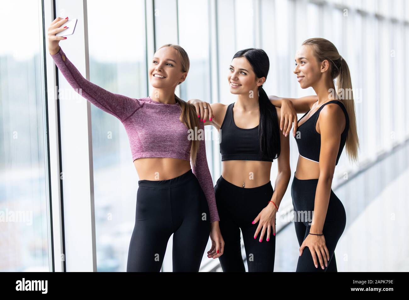 Young girls in sportswear taking selfie in gym. Three female friends in  healthclub taking selfie with mobile phone Stock Photo - Alamy