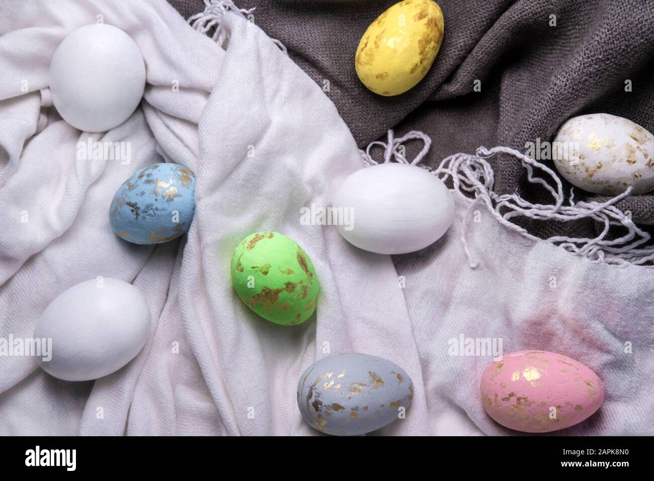 Easter eggs multicolored on the fabric. Easter background with eggs and feathers. Stock Photo