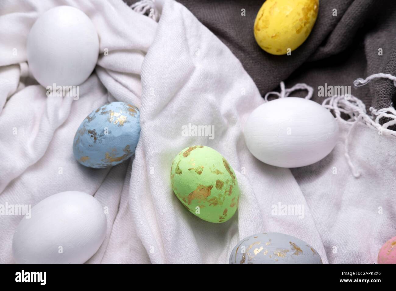 Easter eggs multicolored on the fabric. Easter background with eggs and feathers. Stock Photo