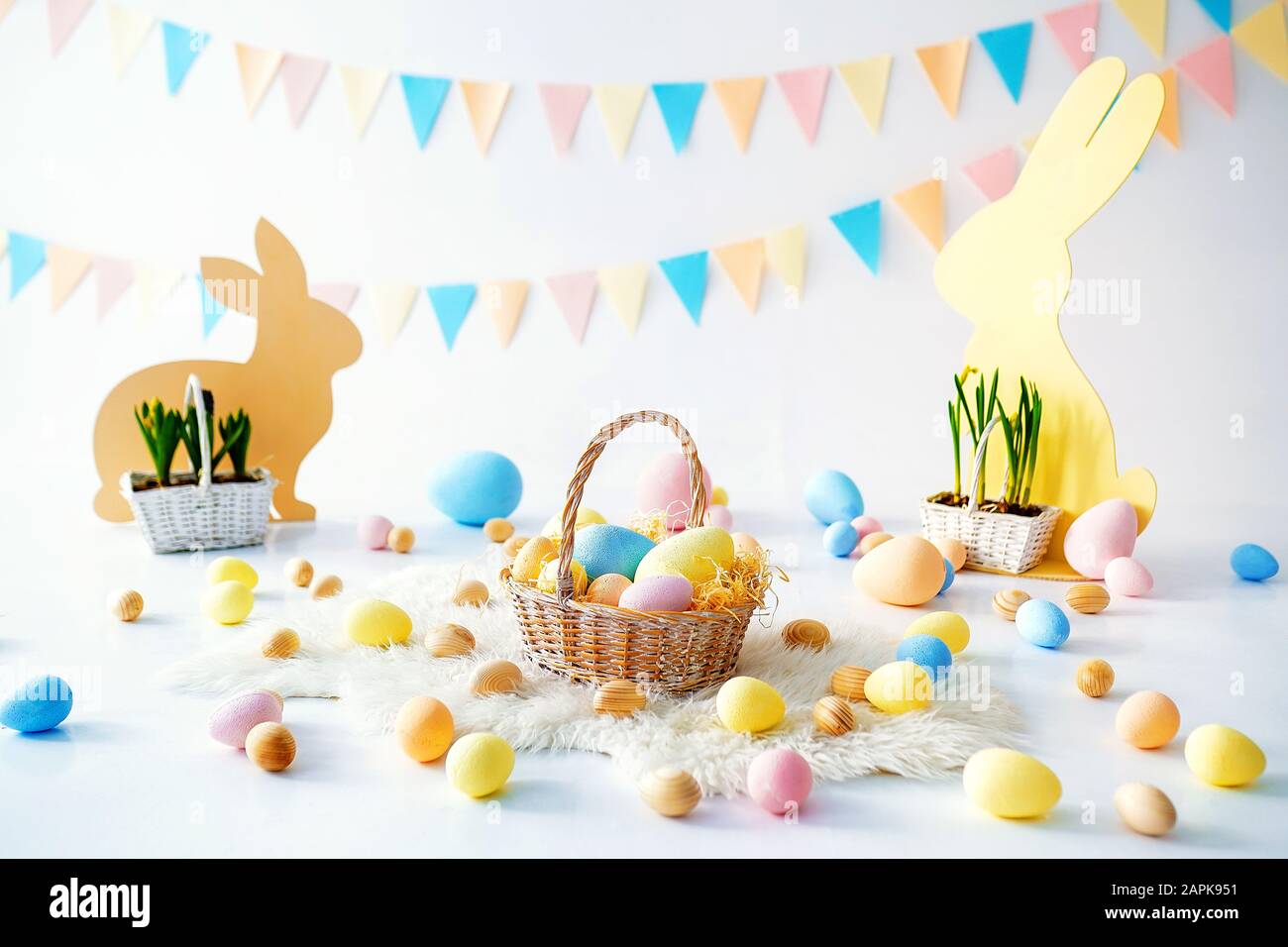 Easter. Many colorful Easter eggs with bunnies and baskets. Easter decoration of the room, children's room for games. Basket with carrots and rabbits. Easter photo shoot. Nest, eggs, boxes of hay. Stock Photo