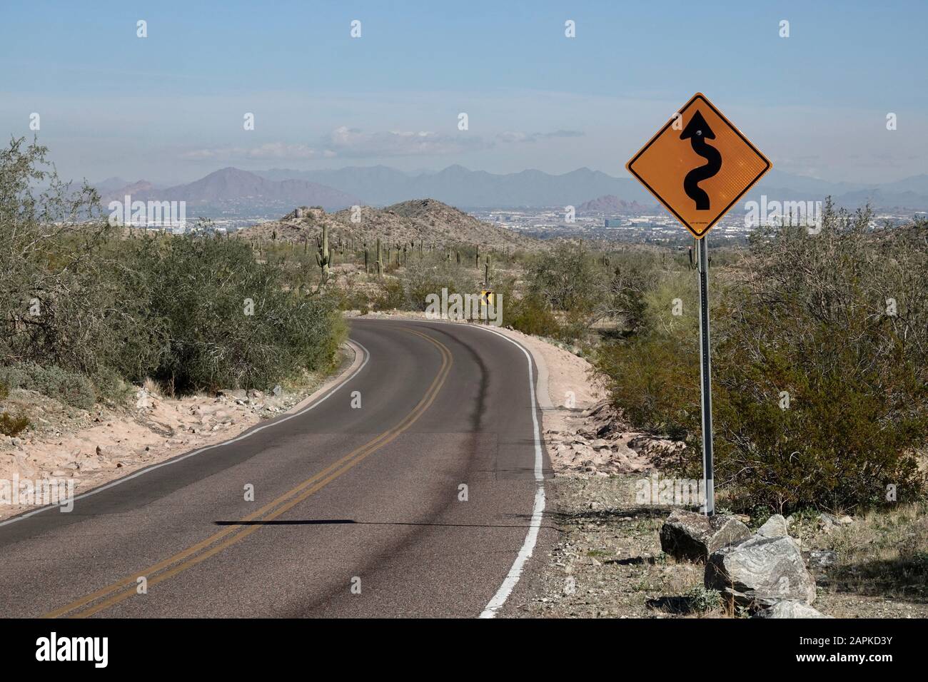 A street sign warning curves ahead for drivers driving through the Arizona desert. Stock Photo