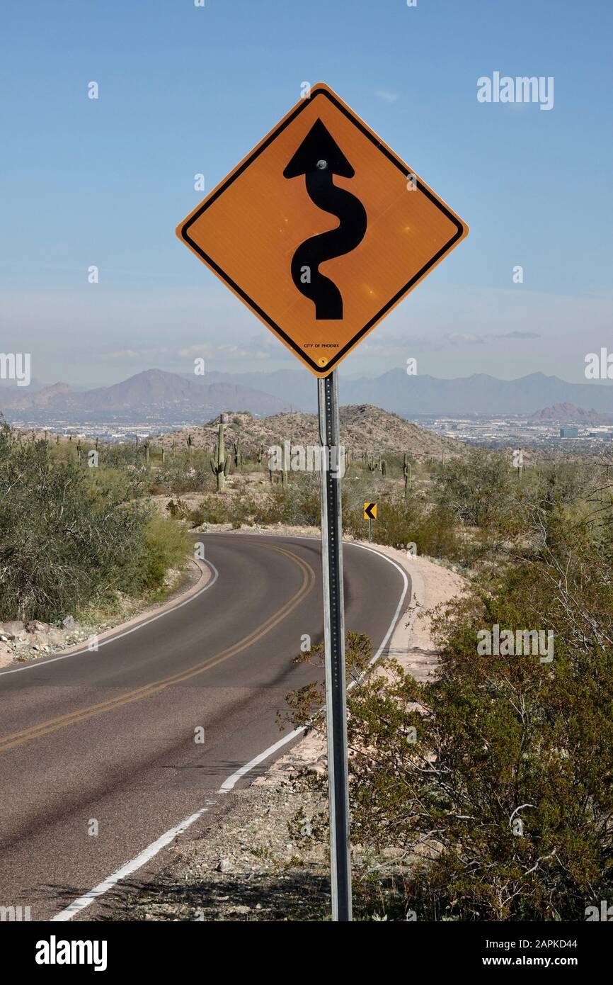 A street sign warning curves ahead for drivers driving through the Arizona desert. Stock Photo