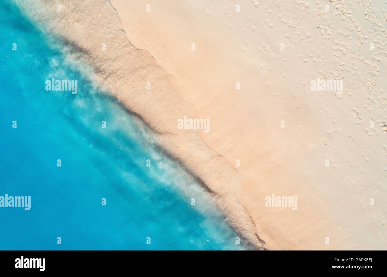 Aerial view of clear blue sea with waves and empty sandy beach Stock Photo