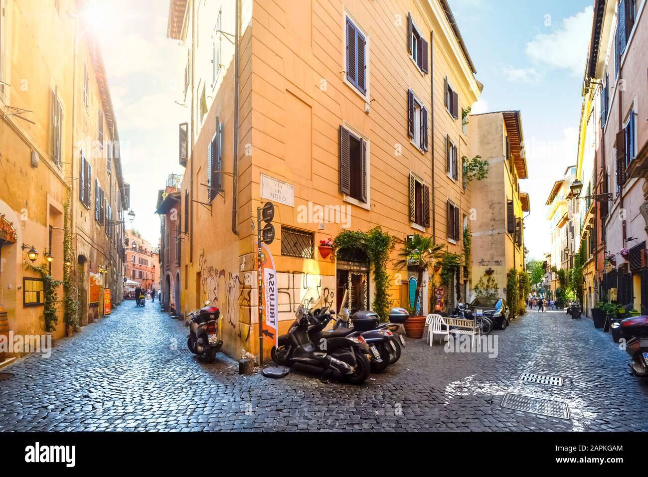 Picturesque, colorful cobblestone street with motorcycles parked and shops in the Trastevere district of Rome Italy. Stock Photo