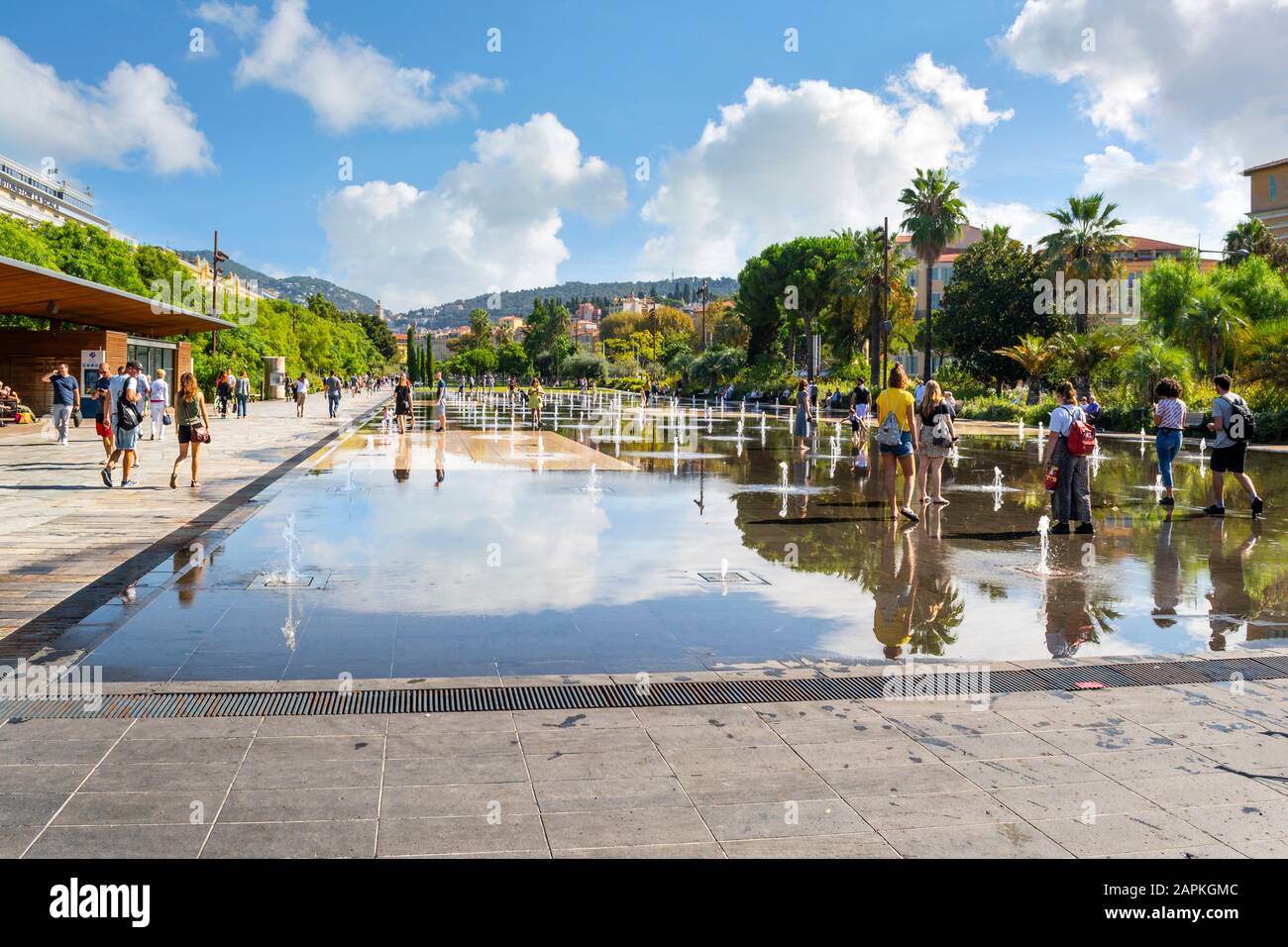 Tourists and local French enjoy a sunny day at Promenade du Paillon water feature in the town