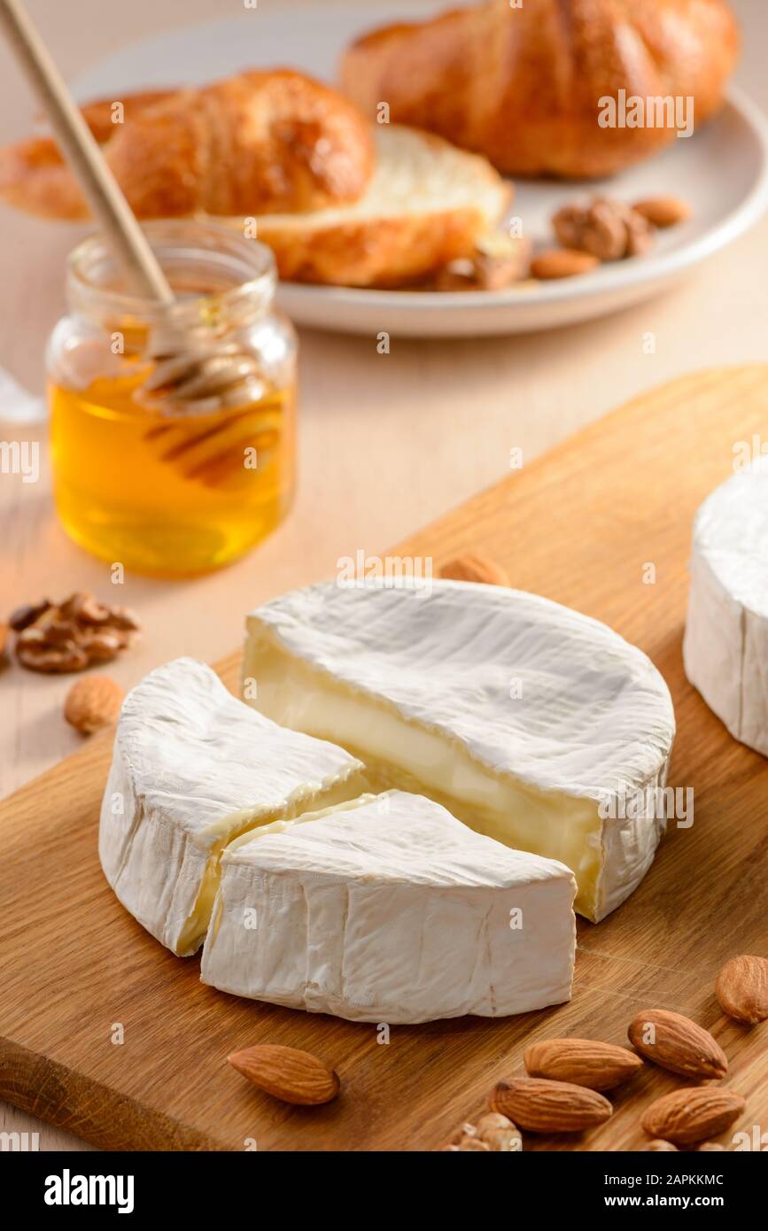 Brie cheese, almonds, honey and croissant on a cutting board Stock