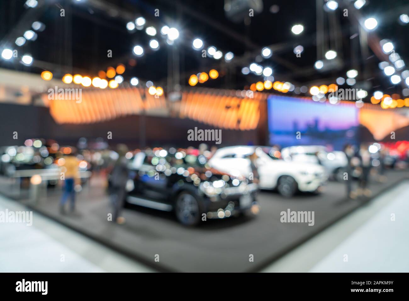 Blurred background of new cars displayed in luxury showroom with light bokeh, motor show event. Stock Photo