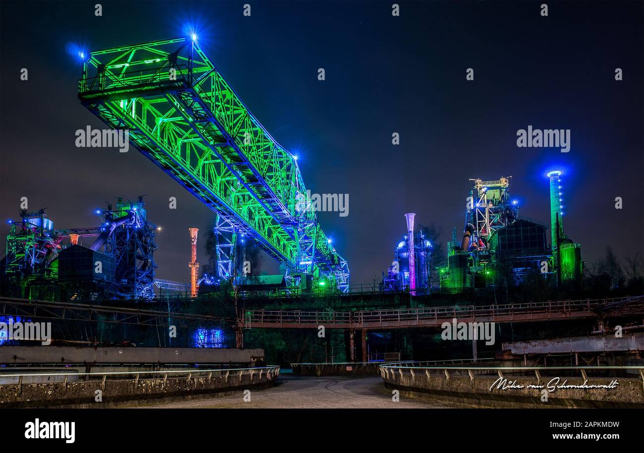 Wide shot of an industrial building and towers covered with neon lights at night Stock Photo