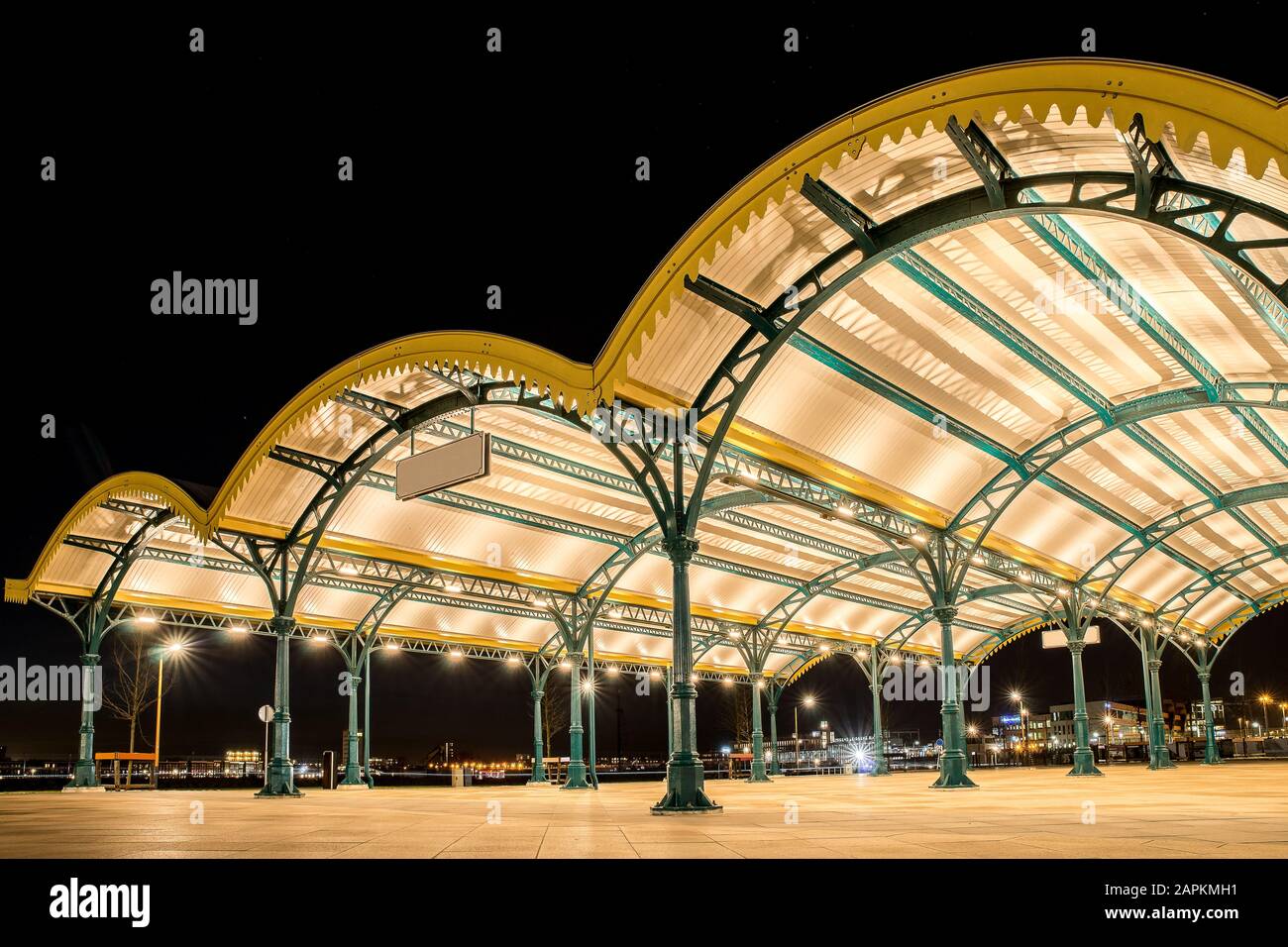 Angled shot of three yellow curved roofs in a city with lights under a dark sky Stock Photo