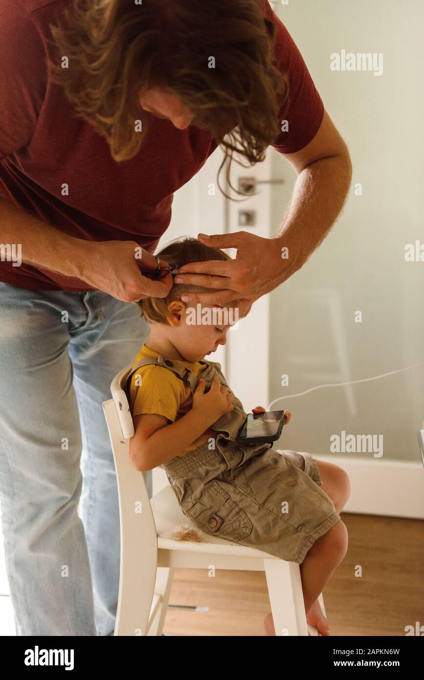Dad cutting hair to little son at home Stock Photo