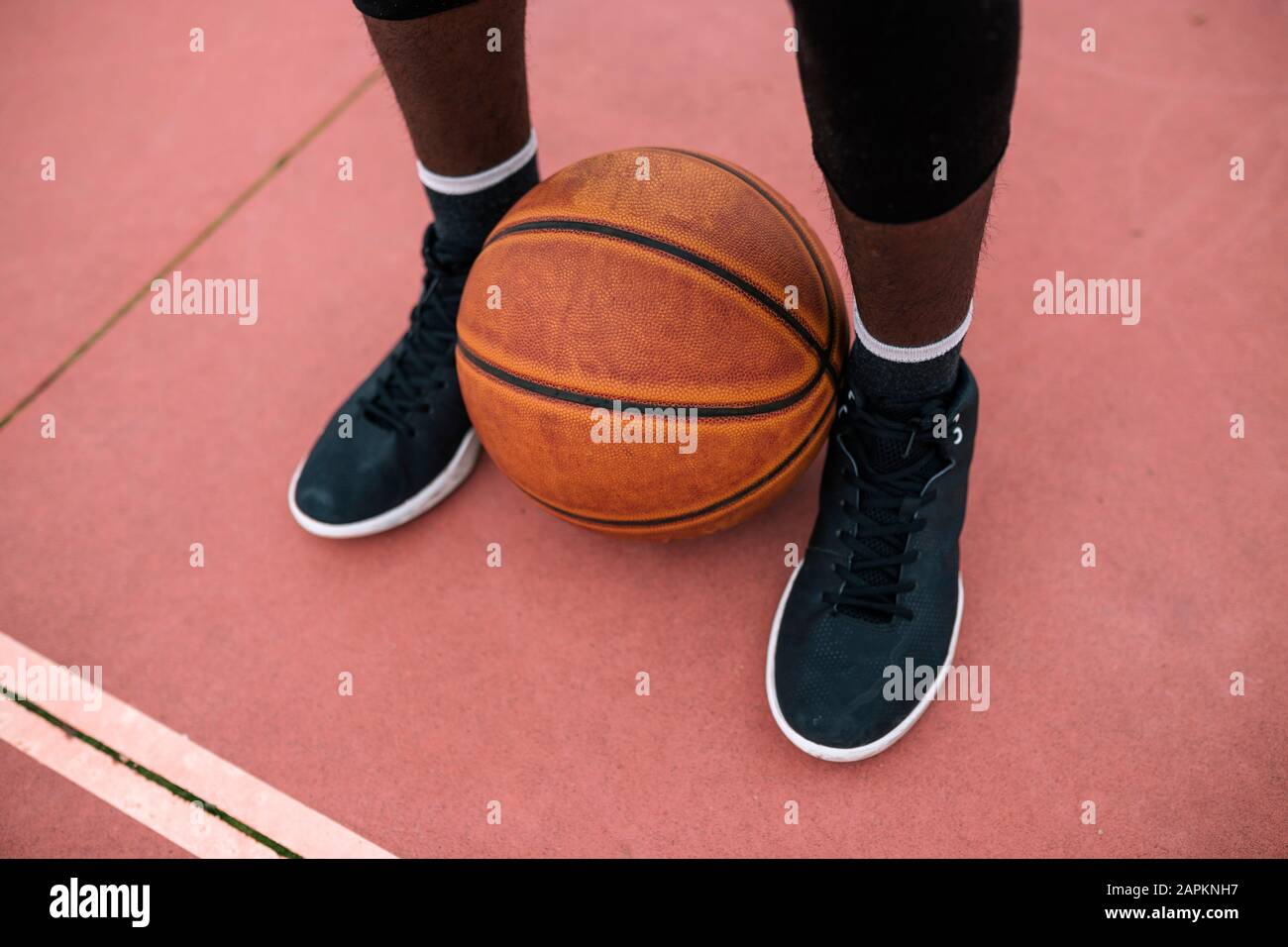 Basketball between feet of basketball player Stock Photo Alamy