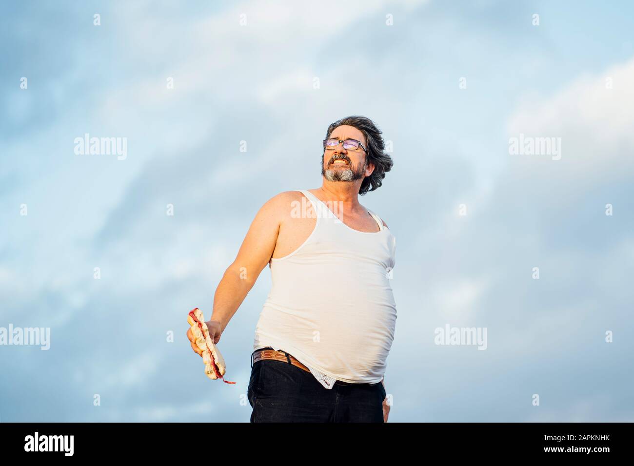 Man with beer belly holding sandwich Stock Photo