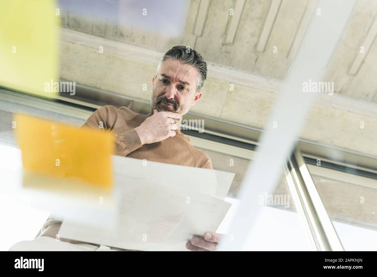 Mature businessman working on adhesive notes on glass table in office Stock Photo