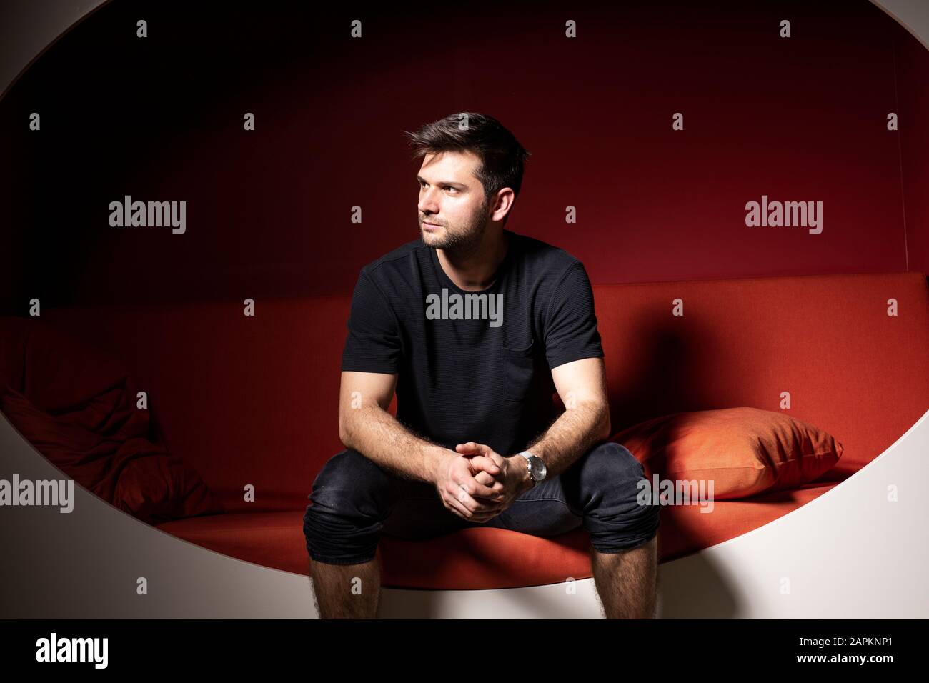 Young man sitting on couzch, thinking Stock Photo