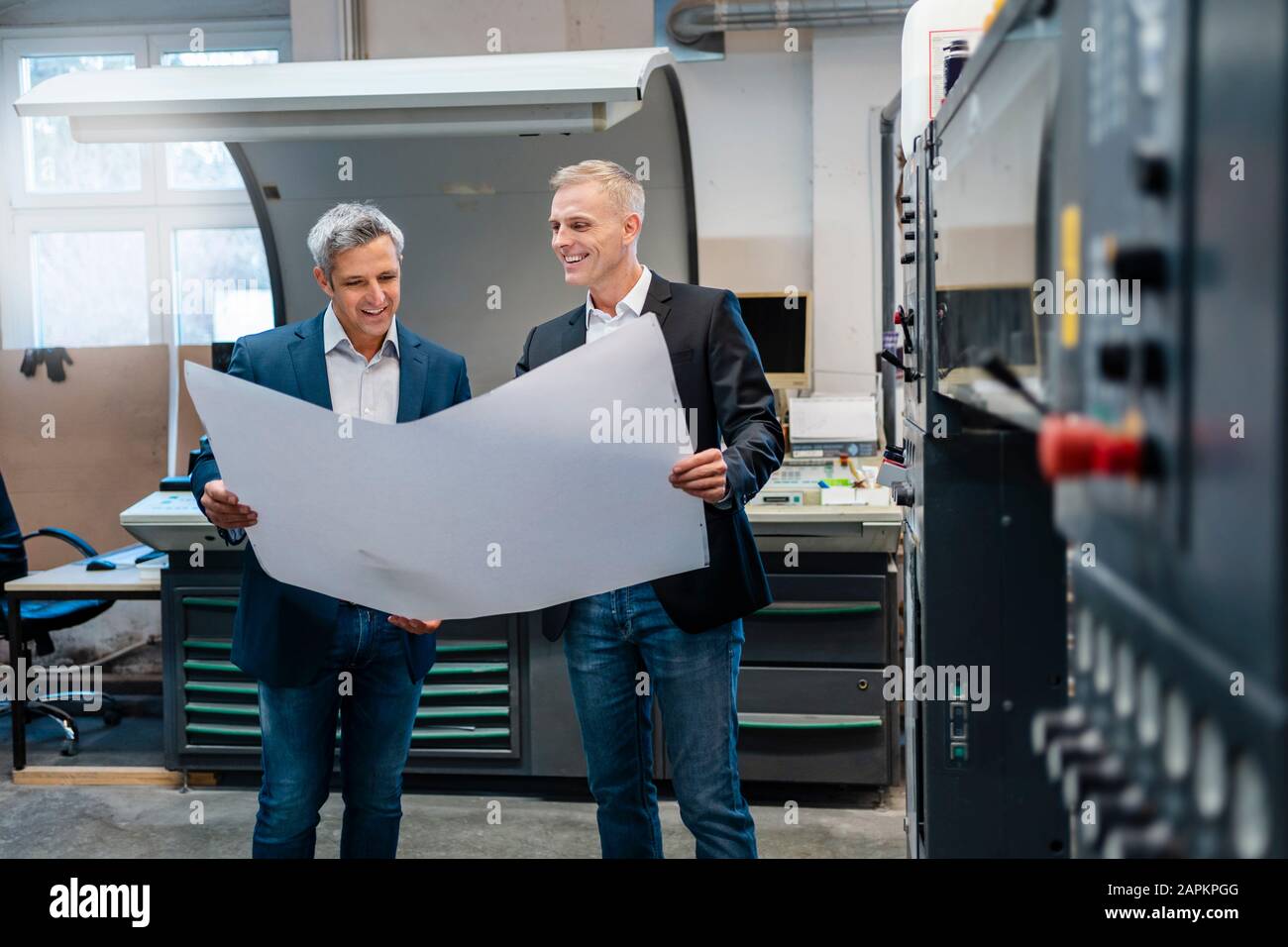 Two smiling businessmen discussing a plan in a factory Stock Photo - Alamy