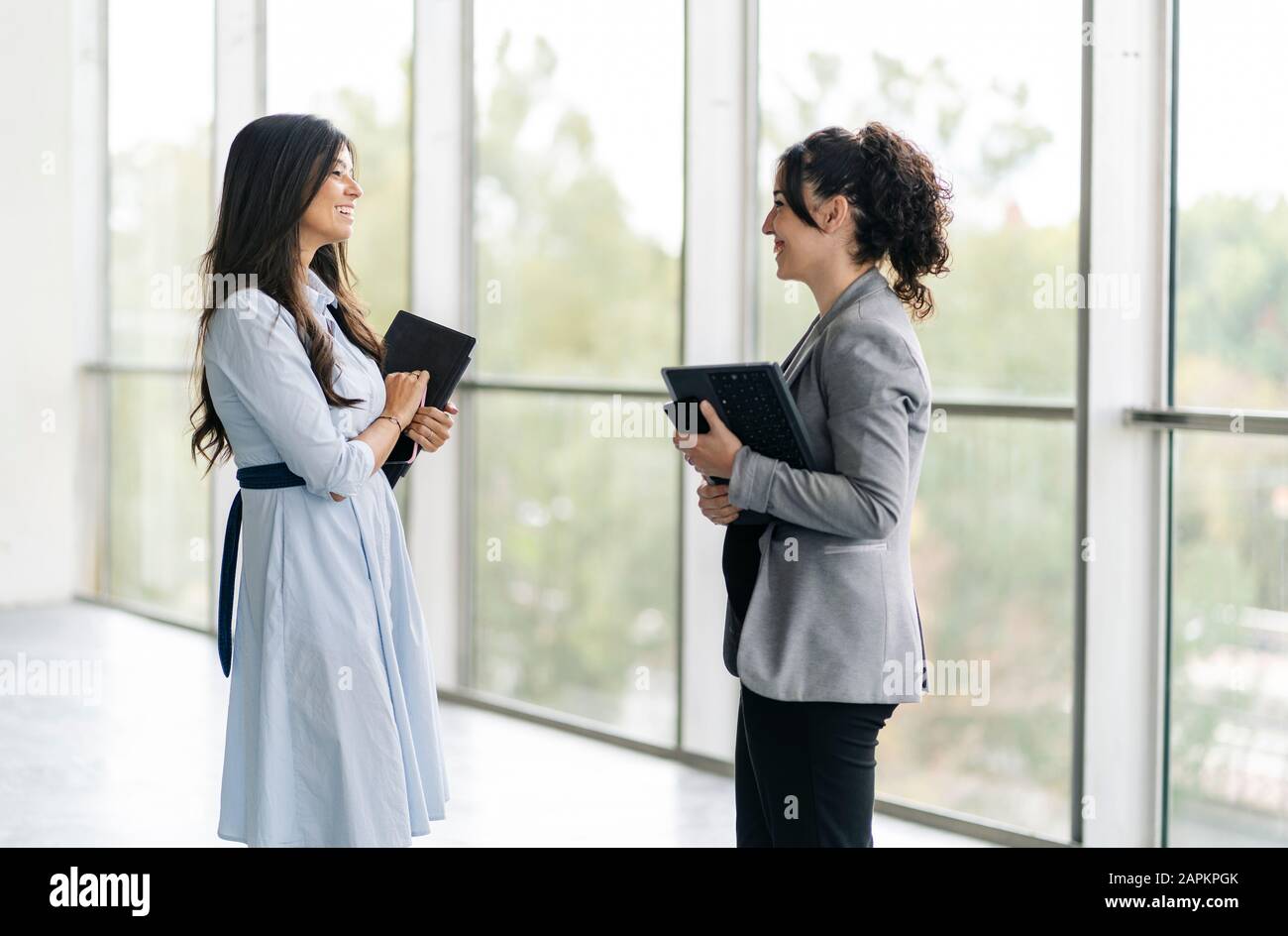 Two happy businesswomen talking at the window Stock Photo