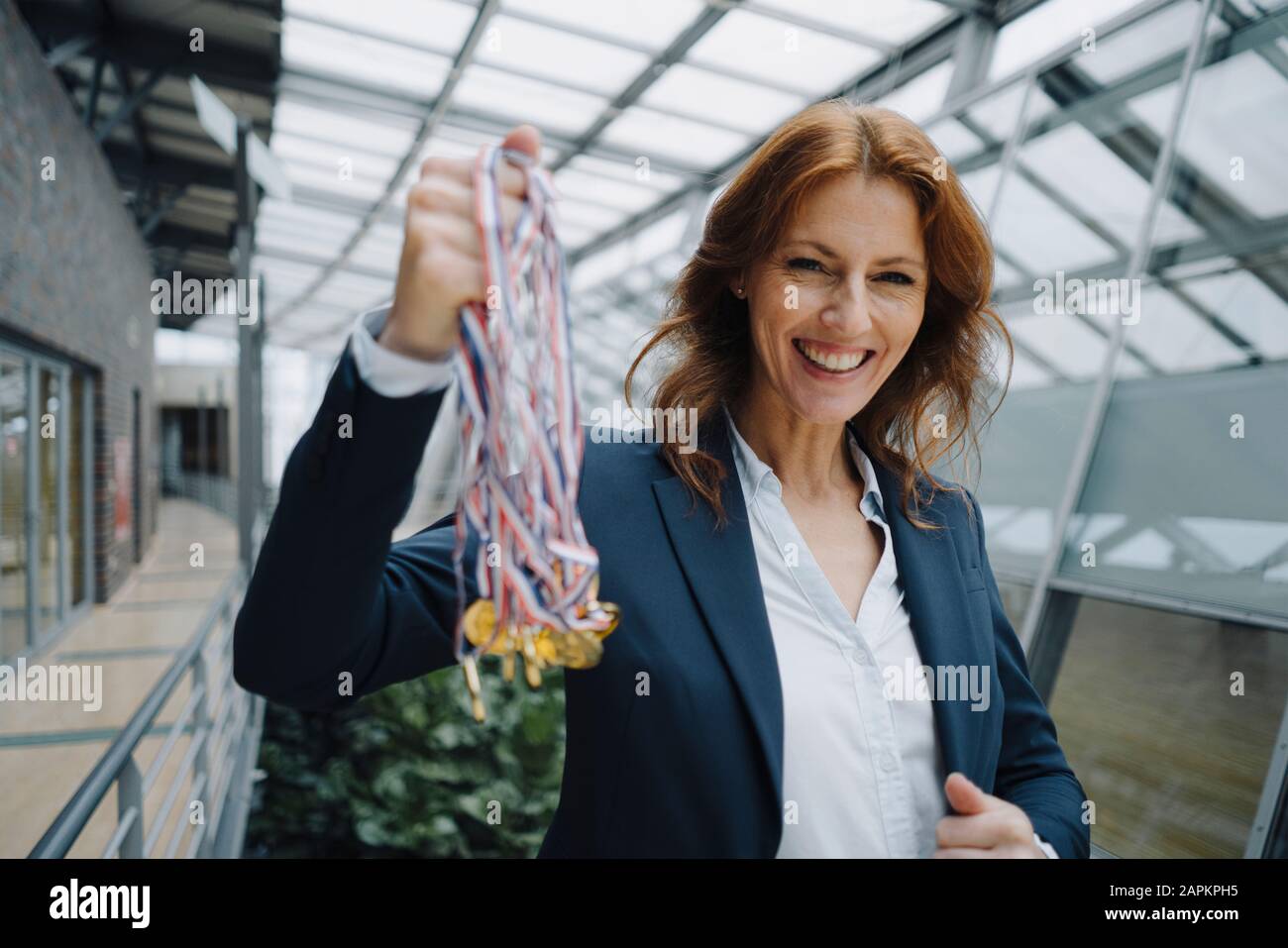 Portait of a happy businesswoman holding medals in office Stock Photo