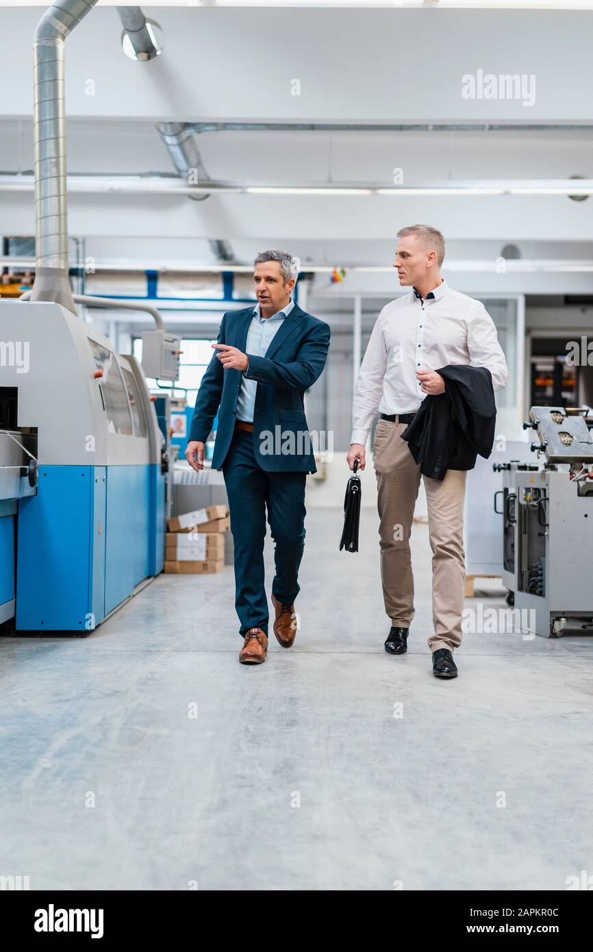 Two businessmen walking and talking in a factory Stock Photo - Alamy