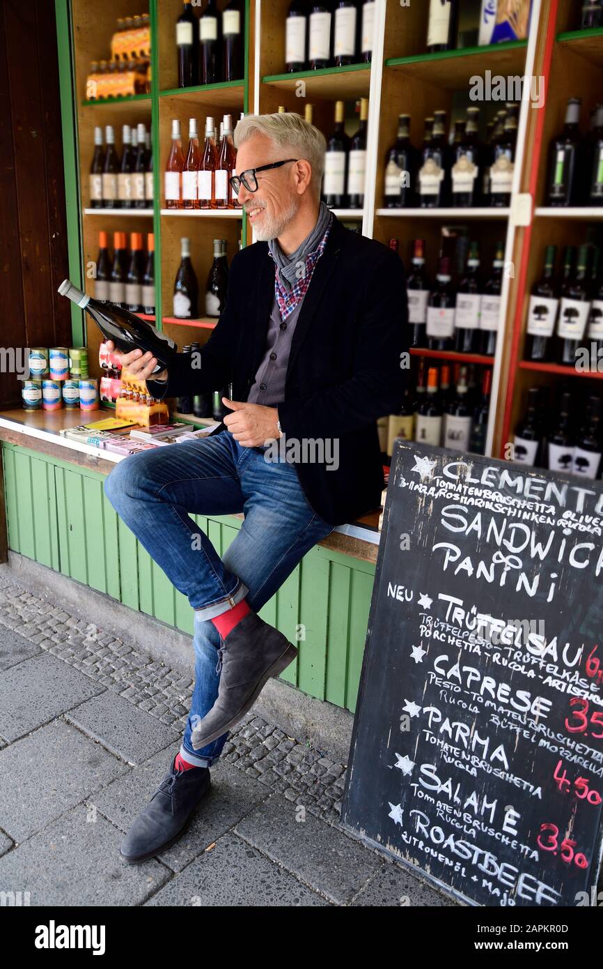 Mature man choosing bottle of wine at a wine shop Stock Photo