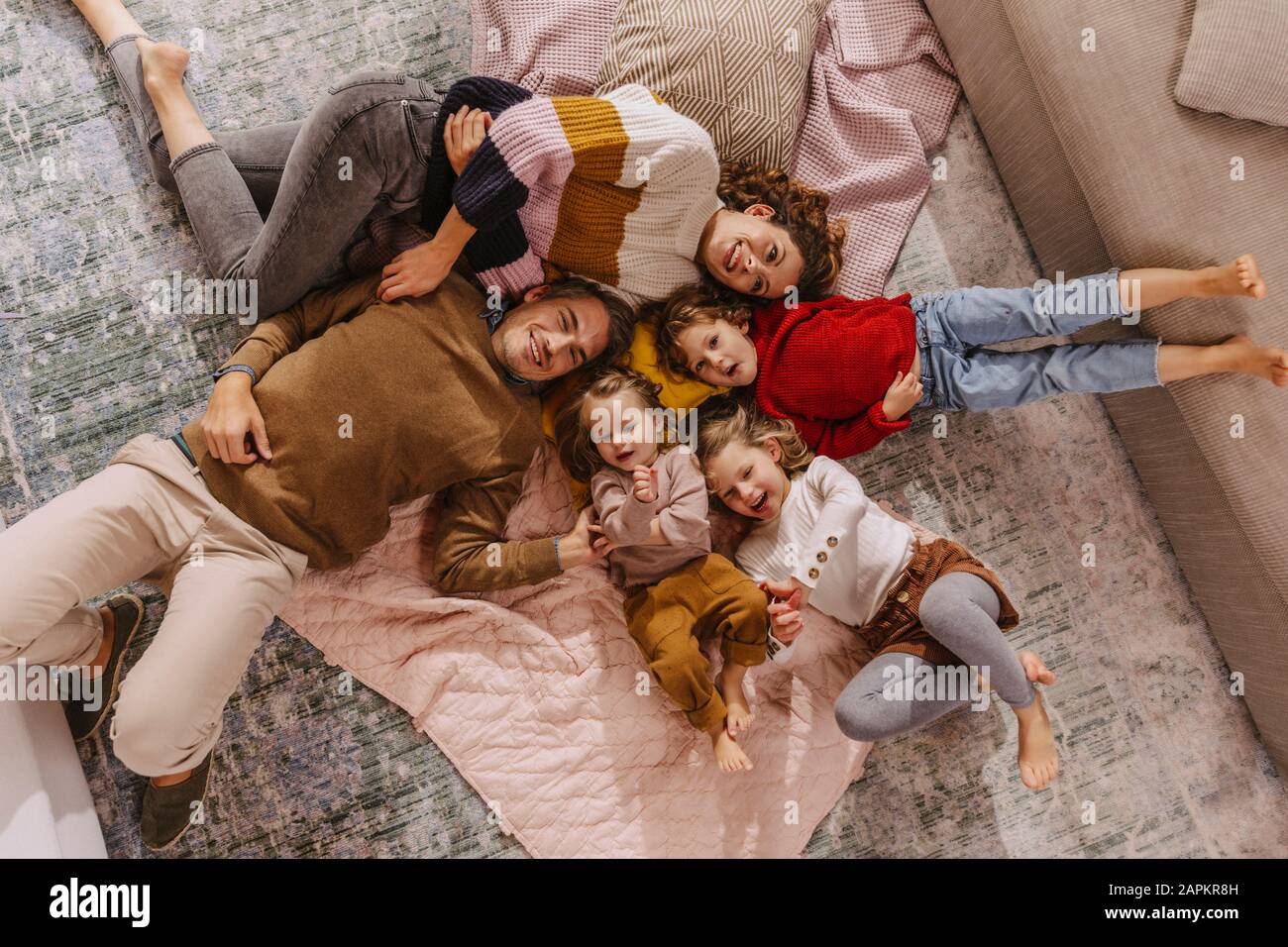 Happy family with three daughters lying on blankets at home Stock Photo