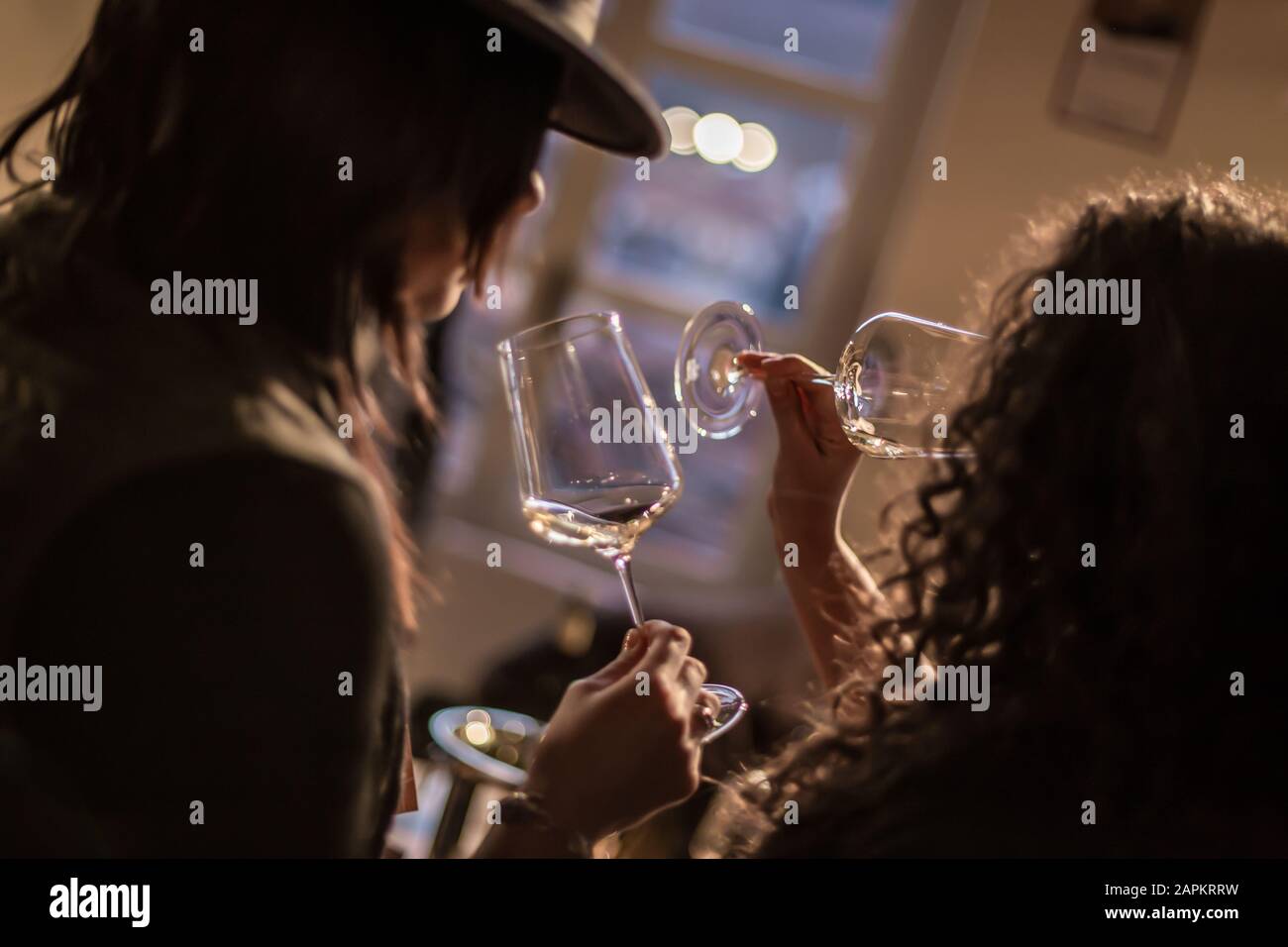 Dutch angle shot of two women drinking wine in a wine glass with a blurred  background Stock Photo - Alamy, image size:1300x956
