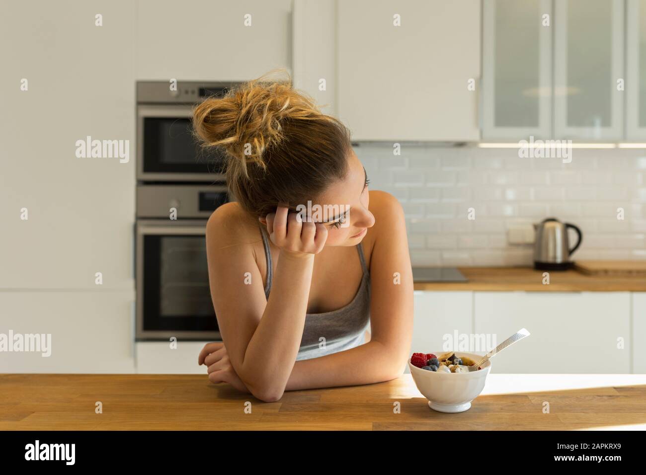 Female teenager during breakfast in the kitchen, looking sideways Stock Photo