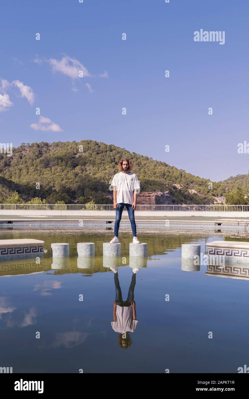 Bearded young man standing on bollards Stock Photo